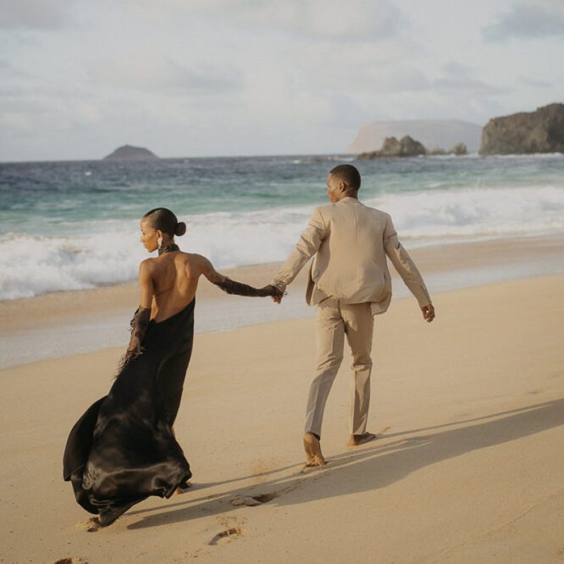 Wedding Photographer Spain Canary Islands Mallorca Groom and bride in a black wedding dress walk together on the beach in Spain